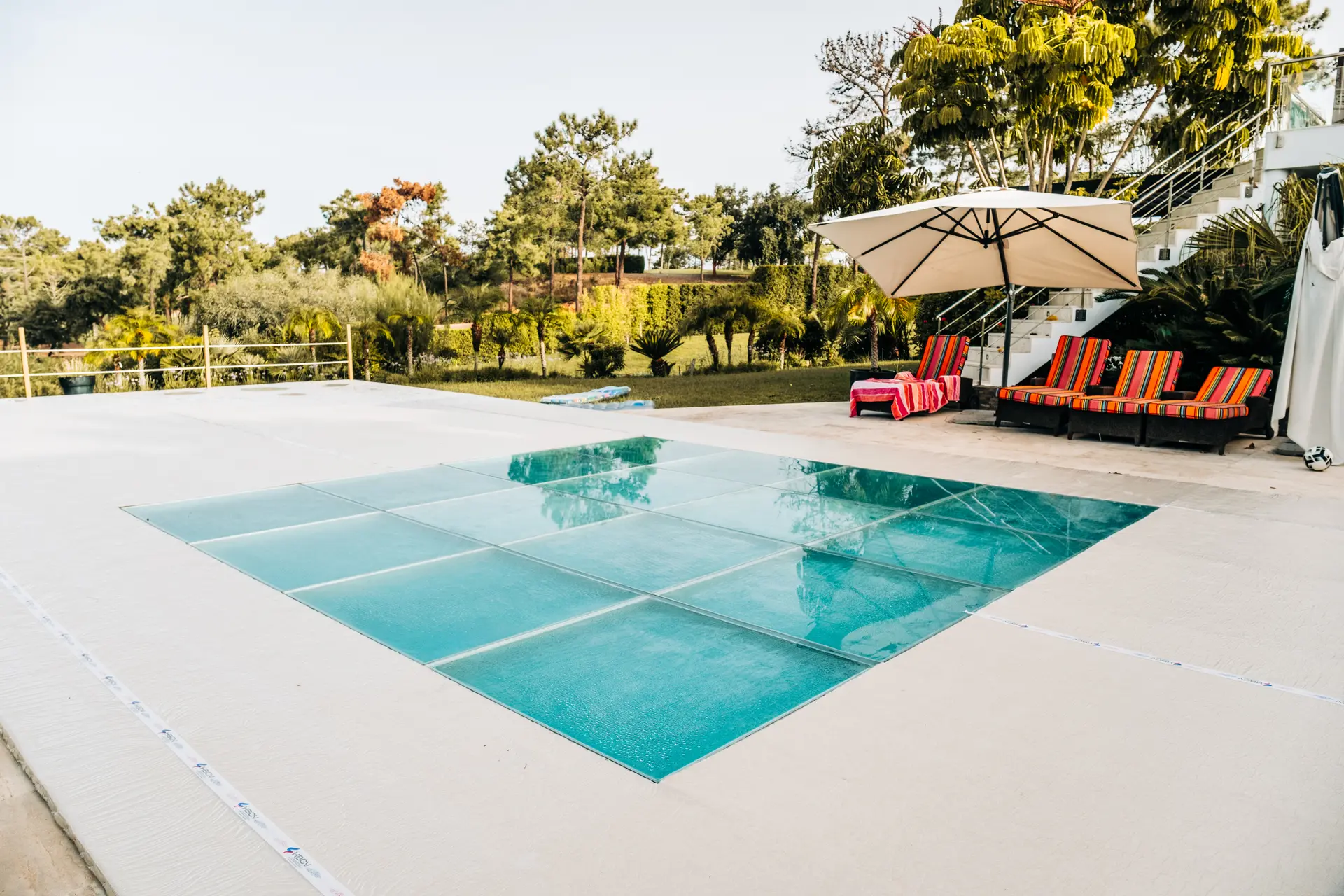 Estrado de vidro montado por cima de uma piscina, ao nível do pavimento