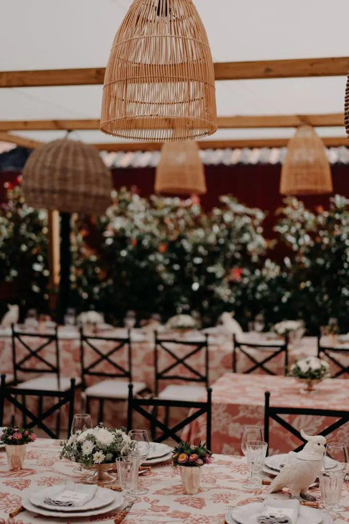 Mesa posta com flores e candeeiros de vime pendurados