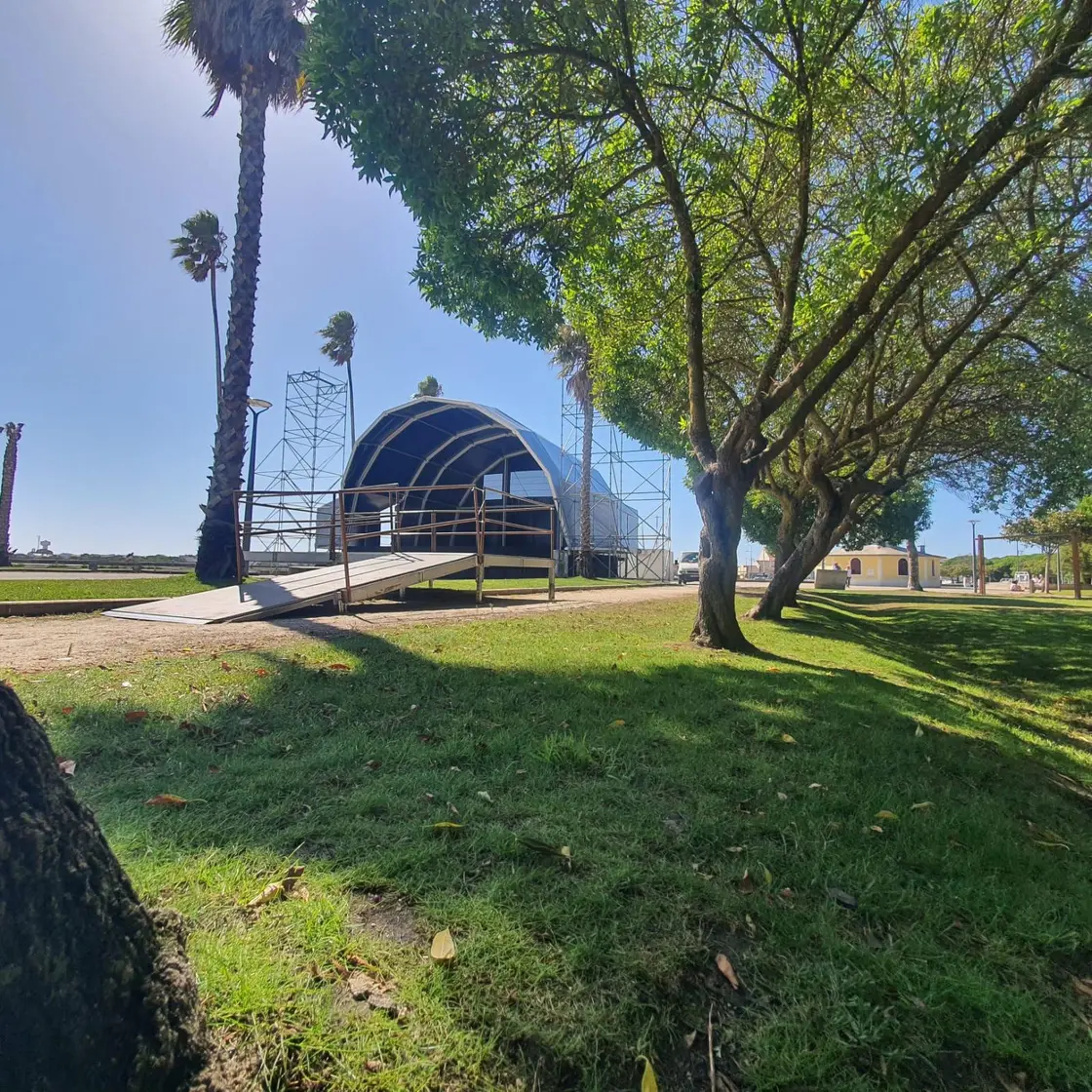 Palco de concha montado num parque relvado, com árvores à volta