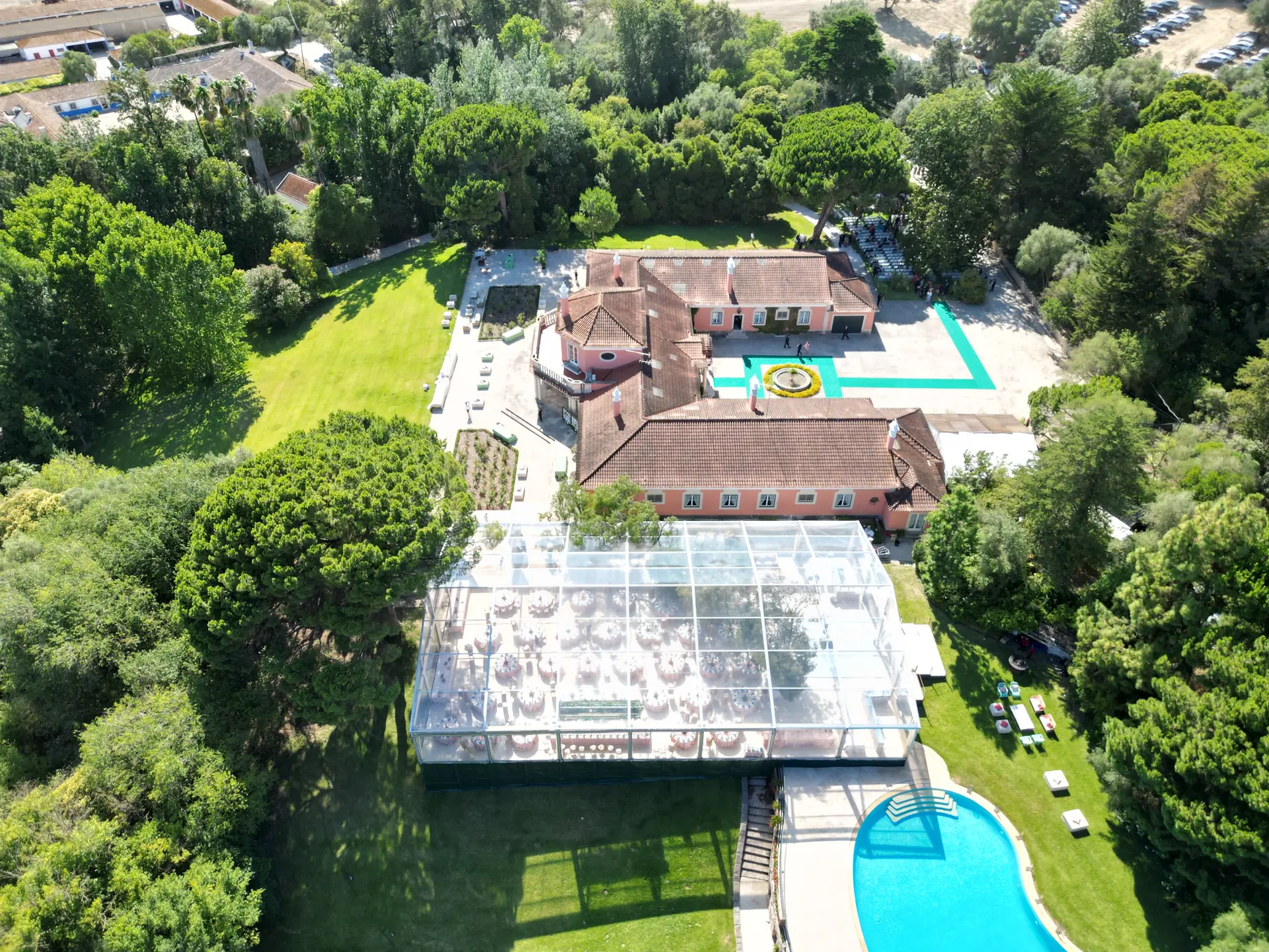 Vista aérea de uma quinta com uma tenda transparente montada no relvado, junto à piscina