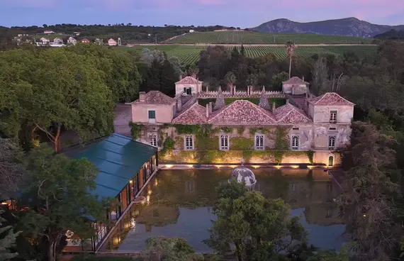 Vista aérea da Quinta das Torres ao anoitecer, com o palácio, o lago e a estrutura nova ao lado